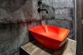 Red washbasin with faucet in expensive loft bathroom in elite sport bar on black brick wall background Royalty Free Stock Photo