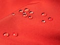 Red waterproof fabric with raindrops close up Royalty Free Stock Photo