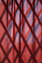 Red wavy natural fabric curtain over wooden partition made of bamboo slats, natural oriental decor