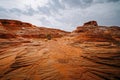 Red wavy sand stones, bluffs and cliifs at Glen Canyon National Recriation Area, Page, Arizona, and cloudy sky background Royalty Free Stock Photo