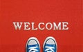 Red welcome carpet with blue sneakers on it. welcome sign concept