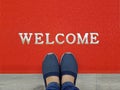 Red welcome carpet with foot-ware on it