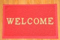 Red welcome carpet on wooden background