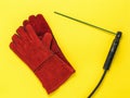 Red welder`s gloves and a handle with an electrode on a yellow background Royalty Free Stock Photo