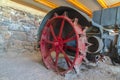 Red wheel rim of an and vintage tractor against stone wall of a farm barn Royalty Free Stock Photo