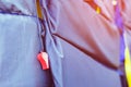 A red whistle with black life jacket hanging on the railing around the walkway for safely of passengers