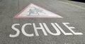 Red and white attention school symbol painted on the grey asphalt during the day, children need protection on the way to school, Royalty Free Stock Photo