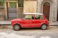 Red and white automobile parked in front of an iconic Italian building