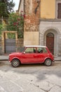 Red and white automobile parked in front of an iconic Italian building