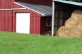 Red and white barn with detached round hay bale storage and green field Royalty Free Stock Photo