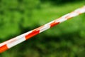 Red and white barrier tape on a fresh green background