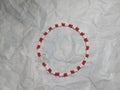 A red and white beaded bracelet with a white butterfly charm on a crumpled paper background