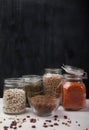 Red and white beans, peas, mung bean, red lentils in glass jars stand on a white wooden table on a black background. vertical Royalty Free Stock Photo