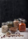 Red and white beans, peas, mung beans, red lentils in glass jars and a wooden spoon on a white wooden table on a black background Royalty Free Stock Photo