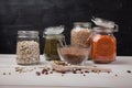 Red and white beans, peas, mung beans, red lentils in glass jars and a wooden spoon on a white wooden table on a black background Royalty Free Stock Photo