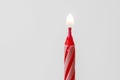 Red and white birthday candle lit on a white background. Birthday concept