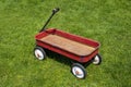 Red white and black four wheeled child pull wagon outdoors in grassy backyard Royalty Free Stock Photo