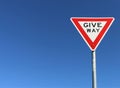 Red, white and black give way sign in a cloudless blue sky