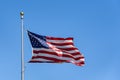 Red, white, and blue of an American flag flying in a breeze against a bright blue sky Royalty Free Stock Photo