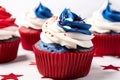 Red, white and blue cupcakes with white frosting and sprinkles. AI generative image.