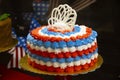 Red white and blue patriotic cake with bokeh holiday decorations behind and a chocolate cake blurred to the side Royalty Free Stock Photo