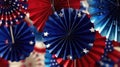 Red, white and blue patriotic theme. There are several paper fans hanging from ceiling in various sizes, with some