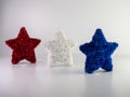 Red, white and blue tinsel stars standing up on a white backgrou