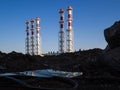 Red-and-white boiler room chimneys against a blue sky. Mountain of stones and debris and pipes boiler station Royalty Free Stock Photo