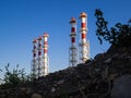 Red-and-white boiler room chimneys against a blue sky. Mountain of stones and debris and pipes boiler station Royalty Free Stock Photo