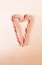 Red-white candy cane. Two heart-shaped lollipops. Traditional Christmas sweetness. Close up. Top view