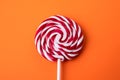 Red and white candy on a stick, lollipop. Orange background Royalty Free Stock Photo