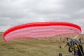 Red and white canopy paraglider lying on green grass against cloudy sky background Royalty Free Stock Photo
