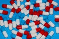 Heap of red white capsules lie on a blue background in the studio Royalty Free Stock Photo