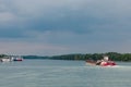 Red, white cargo ship sails along the wide part of River in cloudy weather, parked ships are in distance. selective focus. barge Royalty Free Stock Photo