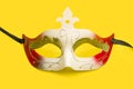 A red and white carnival mask on a yellow background
