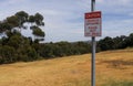 Red and white Caution, Sinkholes Appearing, Please Keep Off The Grass warning sign on a metal pole Royalty Free Stock Photo