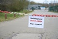 Red white chain barrier in front of a company and sign with German text VorÃÂ¼bergehend Geschlossen, wegen Coronavirus, meaning