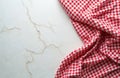 Red, white checkered fabric drapes on cracked marble surface. Gingham tablecloth offers empty copy space for design. Classic Royalty Free Stock Photo