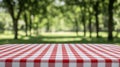 Red and white checkered tablecloth picnic table with blurred green trees and grass background creating peaceful outdoor setting Royalty Free Stock Photo