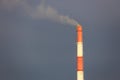 Red and white chimney with smoke against a stormy sky Royalty Free Stock Photo