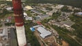 Red and white chimney-stalk above the industrial zone, hangars and other factory buildings surrounded by green forest Royalty Free Stock Photo