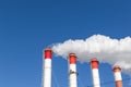 Chimneys of the boiler room, equipped with a traffic light. industrial climbers carry out routine repairs. white smoke on a blue s