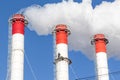 Red-white chimneys of the boiler room, equipped with a traffic light. industrial climbers carry out routine repairs. white smoke