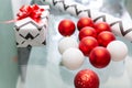 Red and white Christmas balls are scattered on the glass table. Christmas gift, wrapping paper, red bow. New Year, xmas Royalty Free Stock Photo