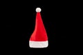 Red and white christmas hat in black background. Santa claus cap on the plain dark background Royalty Free Stock Photo