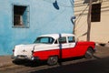 Red and white classic car in front of blue building Royalty Free Stock Photo