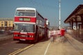 Red and White double decker Leyland Olympian preserved bus at bus stop. Ghostly blurred passengers wait to board and travel