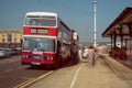 Red and White double decker Leyland Olympian preserved bus at bus stop. Ghostly blurred passengers wait to board and travel