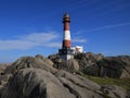 Red white Eigeroy Lighthouse and anorthosite rock formations Royalty Free Stock Photo