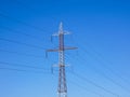 Red white electricity pylon against blue sky